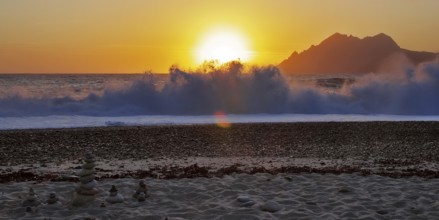 Land art in front of surf waves at sunset on Porto beach, Corsica