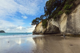 Woman takes pictures of magnificent landscape. Ocean tide in the Cathedral Cove. Mirror reflections
