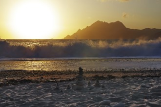 Land art in front of surf waves at sunset on Porto beach, Corsica