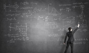 Man in suit standing with back and drawing formulas on chalkboard
