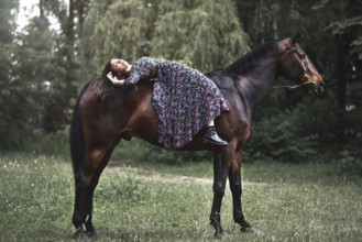 Young pretty girl laying on horseback in the forest