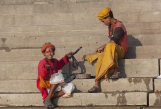 Children with cobra at ghat steps on river Ganges, Varanasi, Uttar Pradesh, India