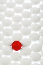 White tablets in contrast with a red tablet, symbolic photo for bullying and individuality