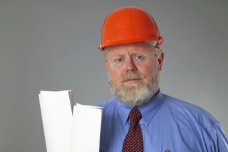 Man in suit with construction helmet on grey background