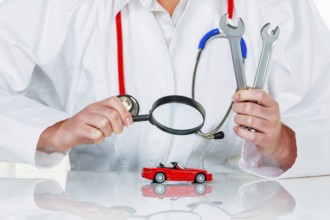 A model of a car is examined by a doctor. Symbol photo for workshop, service and car purchase.