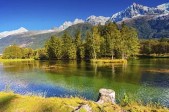 City Park is illuminated by sunset. The lake reflected the snow-capped Alps and evergreen spruce.
