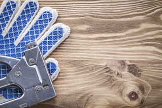 Set of staple gun protective gloves on wooden board