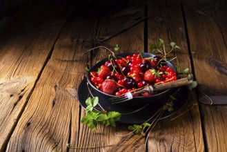 Schüssel mit verschiedenen Früchten wie Erdbeere, rote Johannisbeere und Kirsche