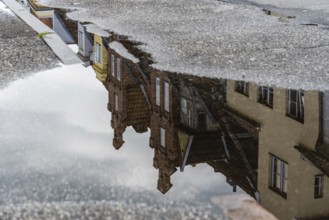 Reflection on water puddle of colorful old gable houses in historic centre of Lubeck, Germany