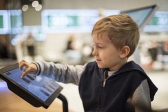 Young boy chooses shopping on the monitor screen in a modern store