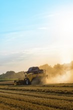 Big combine harvester threshing in the sunset
