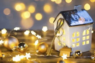 Key to the house with a keychain on a lamp with a Christmas decor. A gift for New Year, Christmas.