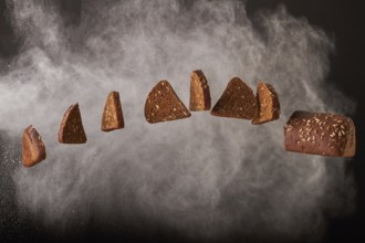Hanging bread slices with sunglower seeds on smoke background. Bakery food concept