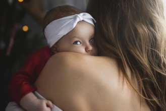 Mother holding cute newborn baby girl in her arms. Sleepy baby yawning