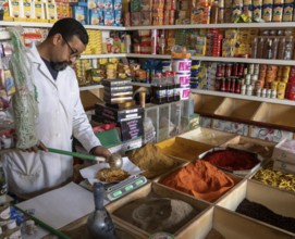 Er-Rich, Morocco, 7 March, 2024: Moroccan shopkeeper mixing spices in his shop in the market of