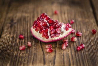 Pomegranate on an old wooden table as detailed close-up shot (selective focus)