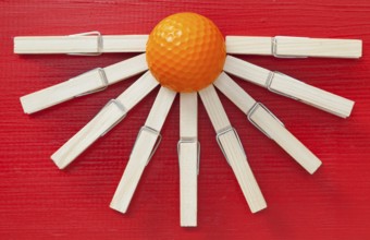 Set of cloth pegs and golf ball on wooden red table