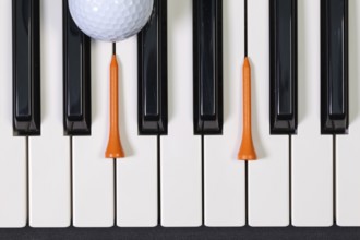Virtuosic game - Piano keyboard and different golf balls and wooden tees