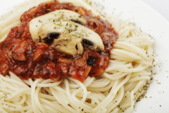 Spaghetti with tomato souce and champignons on white plate