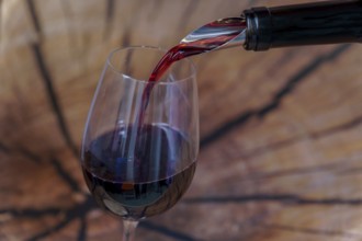 Red wine being poured into a glass on a wooden background