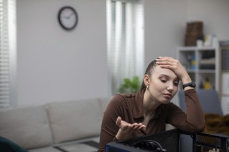 A young woman catches her head in a gesture of helplessness while fixing her computer. A girl sits