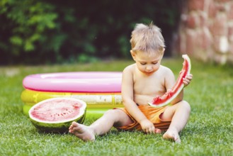 Theme summer seasonal food juicy watermelon berry. small funny Caucasian boy child two years