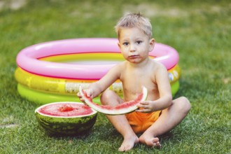 Theme summer seasonal food juicy watermelon berry. small funny Caucasian boy child two years