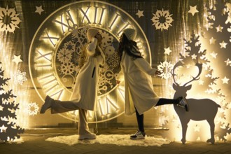 Two girlfriends asian girls in white coats are having fun hugging, new year, light bulbs