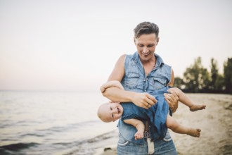 Theme Fatherhood and rest with a child at sea. Young handsome Caucasian father plays plays enjoys