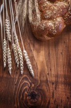 Loaf of breead and wheat ears on vintage wooden board with small copyspace food and drink concept