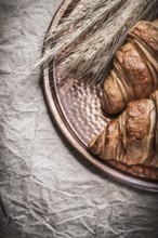 Golden wheat rye ears fresh croissants copper tray on wrapping paper