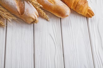 Baguettes and croissant wheat ears on wooden boards with copyspace