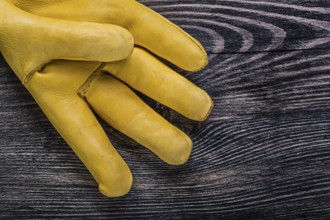 Leather yellow safety glove on vintage wooden board construction concept