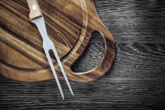 Meat fork cutting board on wood background