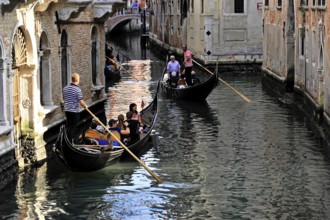 Venice, Veneto, Italy, Europe, Tourists enjoy a gondola ride through the narrow canals between
