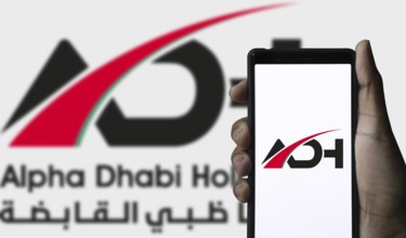 Alpha Dhabi Holding (ADH) logo on smartphone.