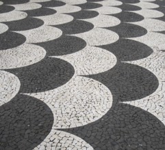 Traditional portugal black and white fish scale pattern tiled cobblestone sidewalk in funchal