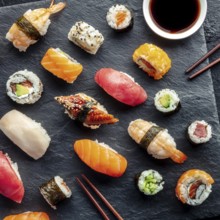 Sushi, overhead square shot with chopsticks and soy sauce. Rolls, maki, nigiri on a black