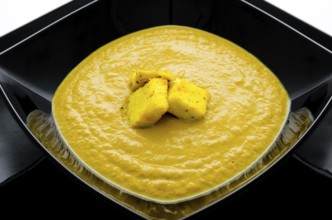 Pea cream soup with croutons in black plate