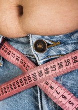 Woman showing fat belly. Pink tape measure