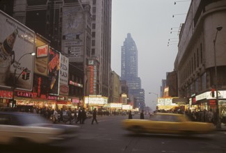 USA New York 1967. Broadway in the evening with cars and people visible and signs on all the