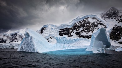 A huge iceberg under a threatening cloudy sky in an icy environment, icebergs in the Southern Ocean
