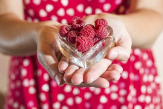 Woman in red dress holding a cup of raspberries