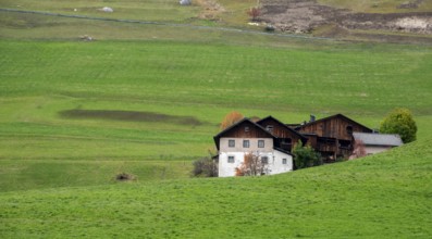 Traditional wooden cottage mountain houses in the green field in the dolomites. Housing in