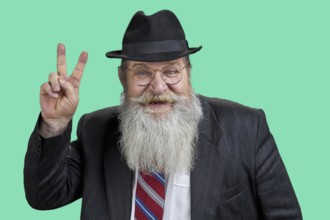 Portrait of happy bearded man showing victory sign. Isolated on green