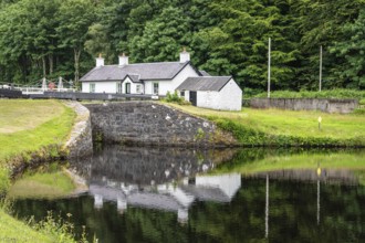 Lock Keepers Cottage reflected in the pool below lock 11, Argyll and Bute, Scotland, United Kingdom