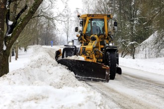 Yellow motor grader Vammas removing snow from street after heavy snowfall in Salo, Finland. January