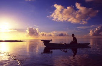 French Polynesia: Woman paddling in a small boat at sunset at Bora Bora Island and Lagoon Resort