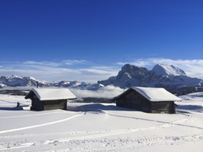 Old wooden barns surrounded by deep snow with skiing tracks in the Dolomites, Italy