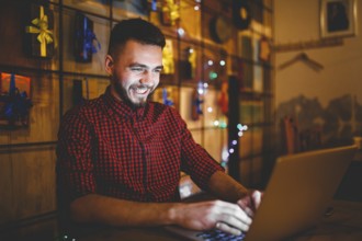 Theme training and computers. A young man with a beard and in a shirt uses a laptop, prints on the